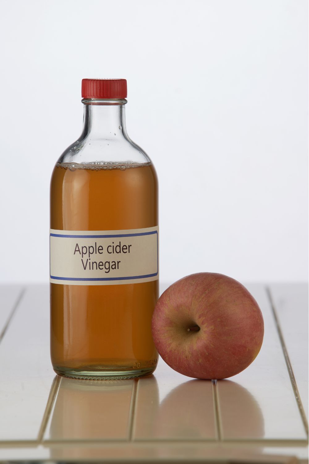 ACV bottle of apple cider vinegar and an apple.